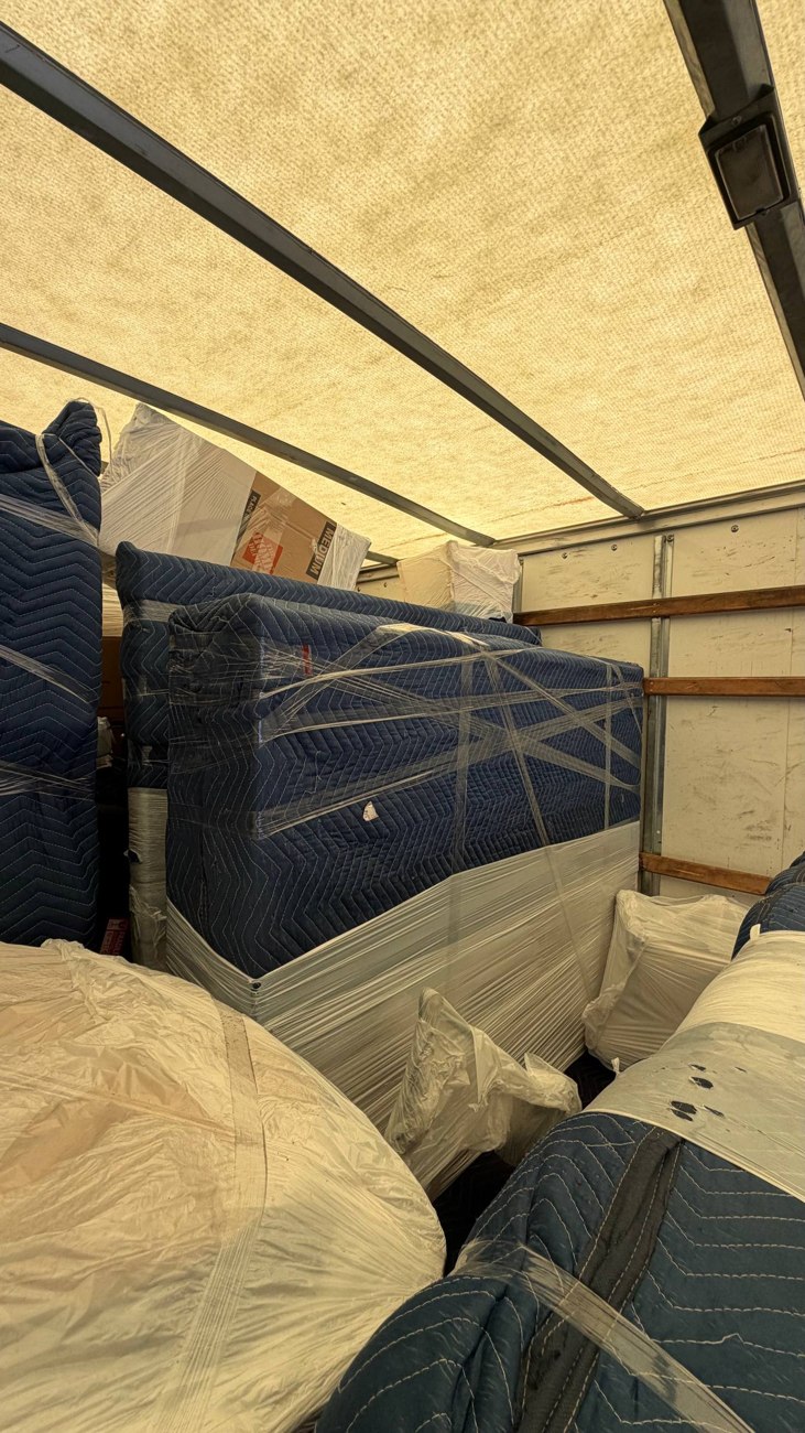Furniture wrapped in quilted moving blankets and stretch wrap inside a truck