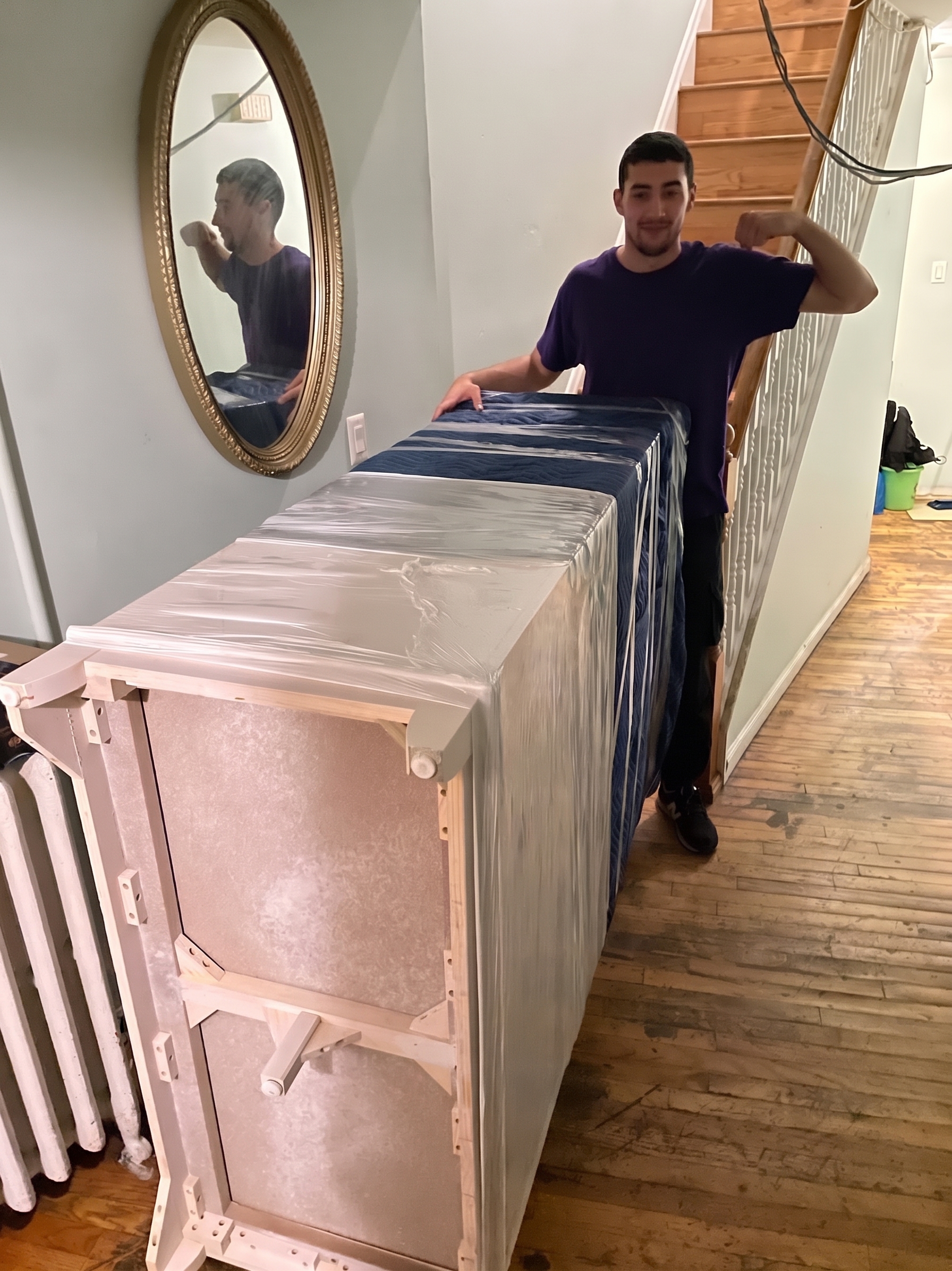 Mover beside carefully wrapped furniture in an apartment hallway