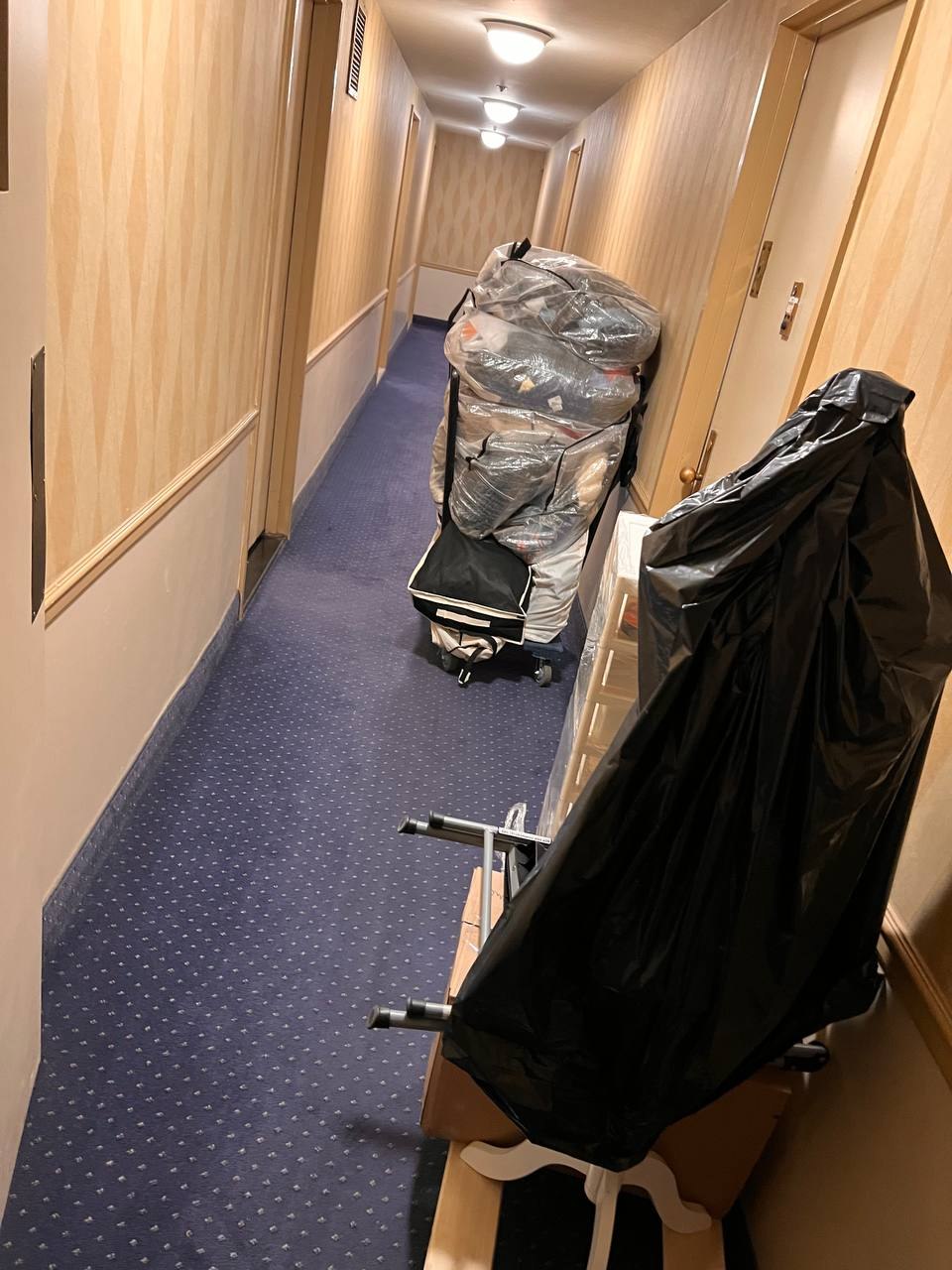 Protected furniture and belongings staged on dollies in a corridor
