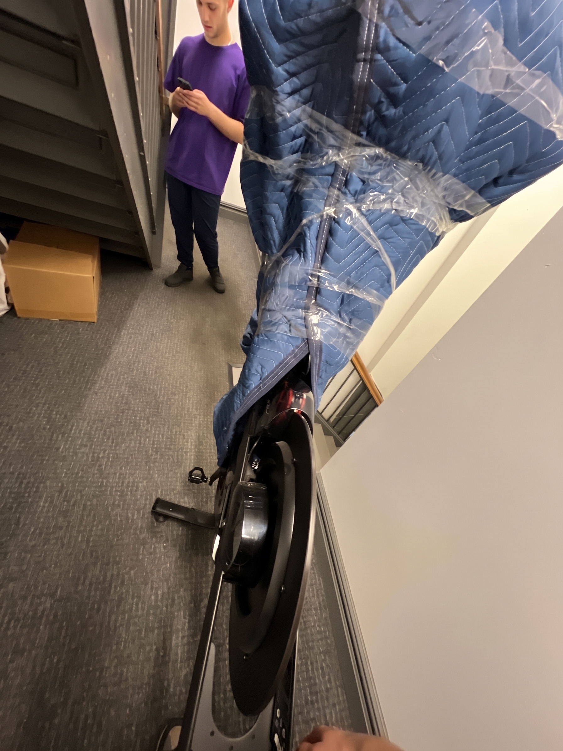 Large exercise equipment protected with a moving blanket in a hallway